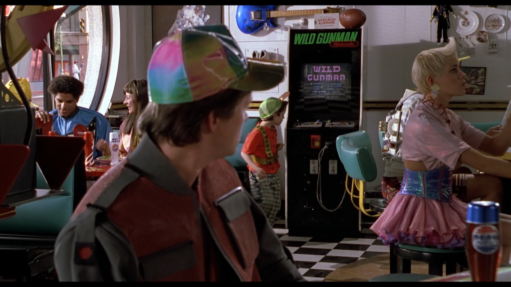 Marty McFly in a Cafe '80s in the future looks at a vintage arcade cabinet. The marquee says Wild Gunman, Nintendo.